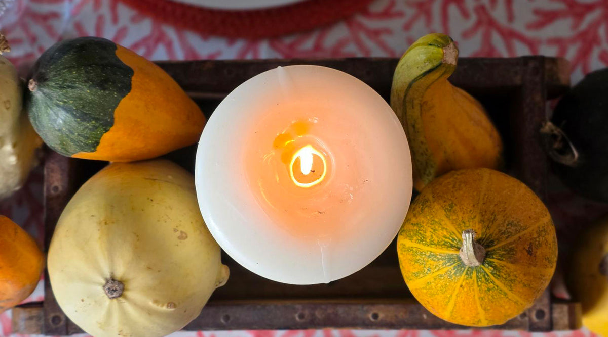 Aerial view of an Autumn centre piece with lit 200 hour candle and gourds.