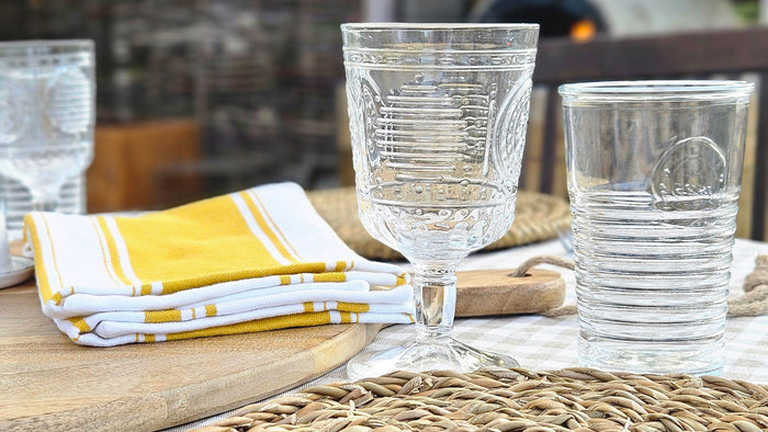 Summer dining table with drinking glasses and tablemats.