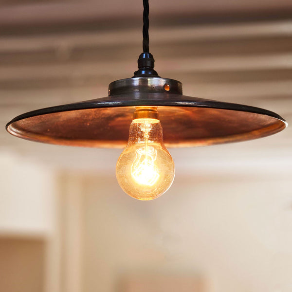 Antique copper pendant shade lit by an Edison bulba retro sty