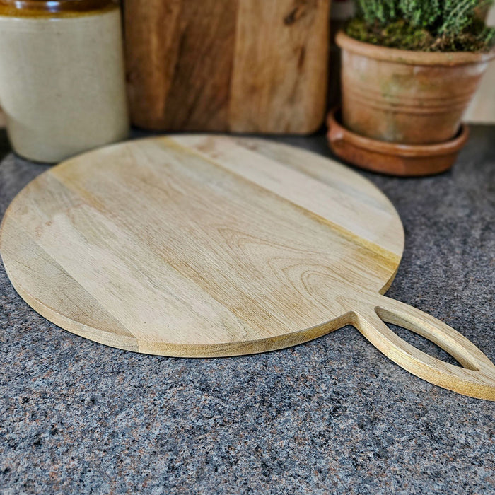 Round wooden cheese board on a work surface
