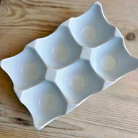 Ivory ceramic egg holder on a wooden surface