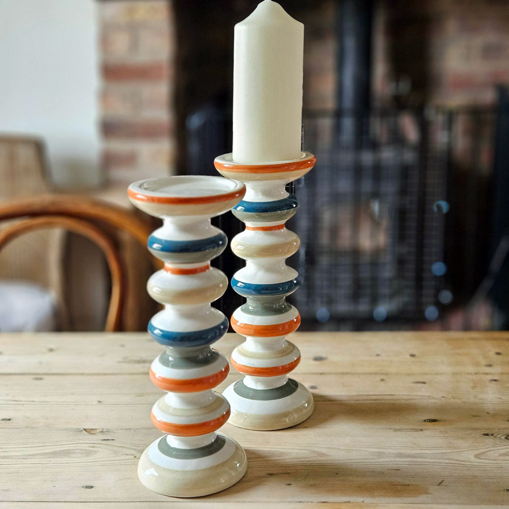 Orange and blue striped candle holder on a pine table