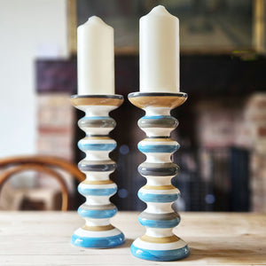 Blue and olive striped ceramic candle holder on a scrubbed table