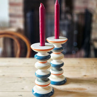 orange and blue striped ceramic candle holder on a scrubbed pine table.