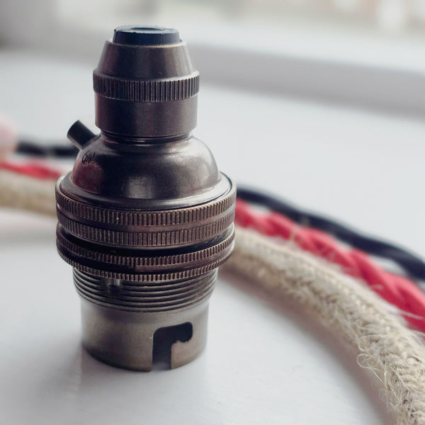 Antique brass metal bulb holder next to vintage style braided cable.