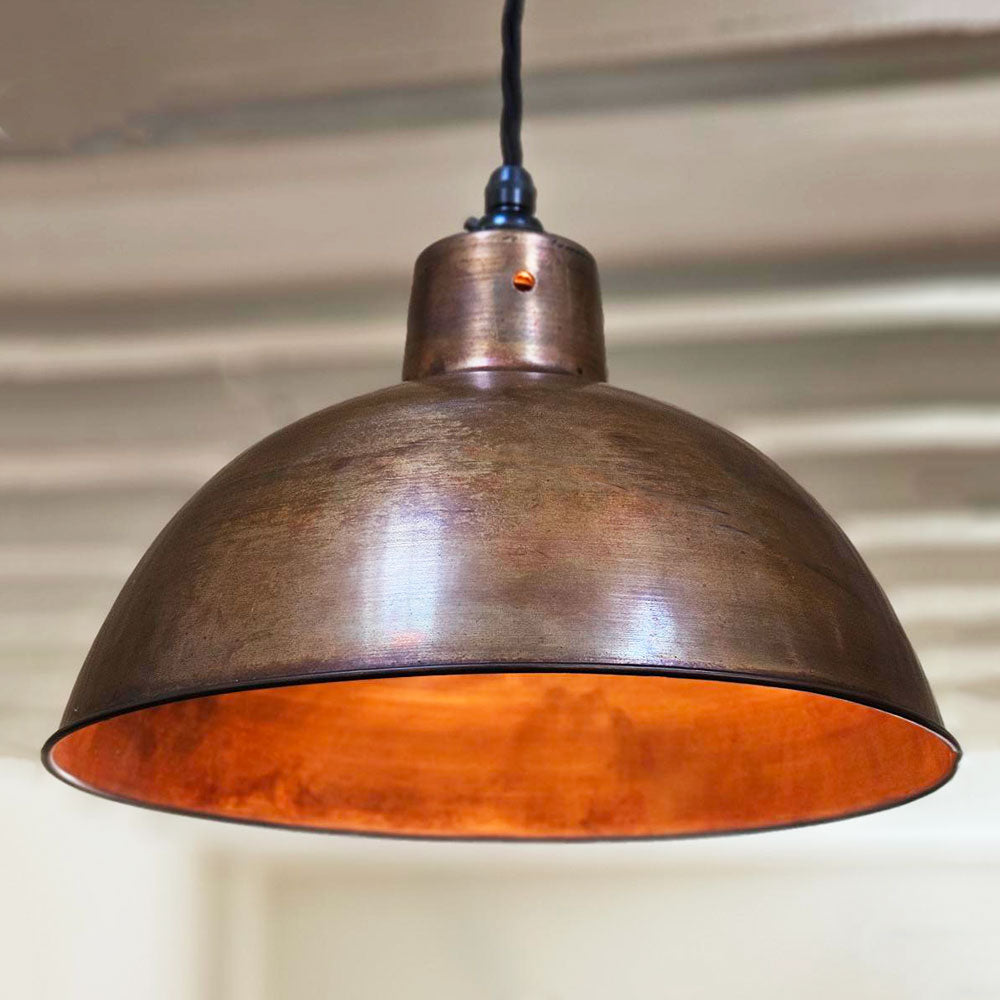 A lit Antique copper pendant shade 300 mm  hanging in a kitchen