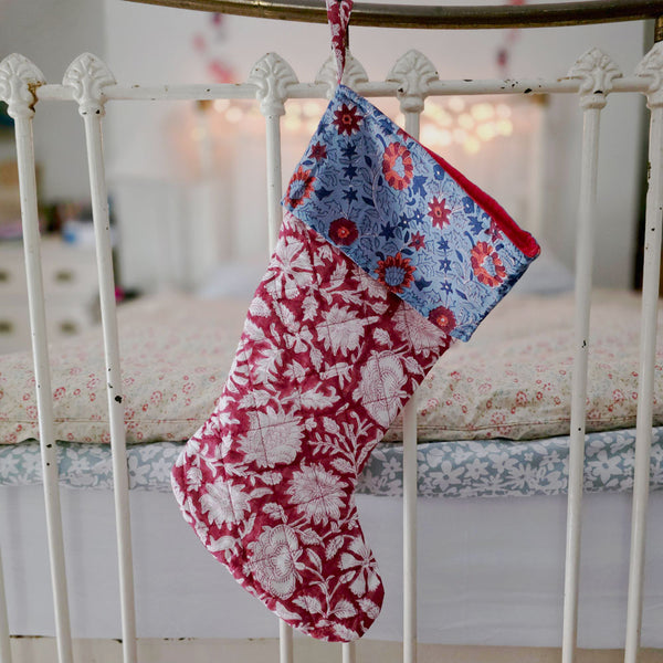 Floral-patterned stockings hanging on a white metal bed frame.