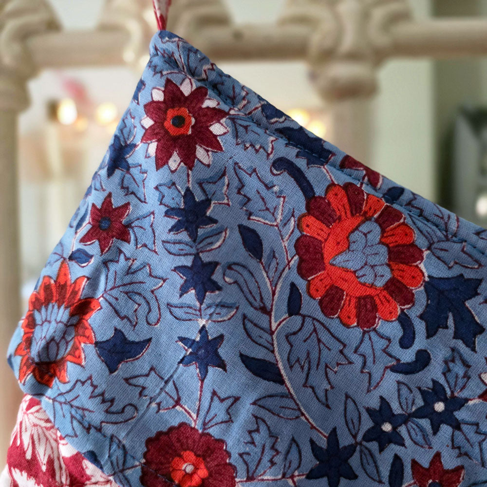 Close up of the top of a fabric Christmas stocking hanging from a bedpost.