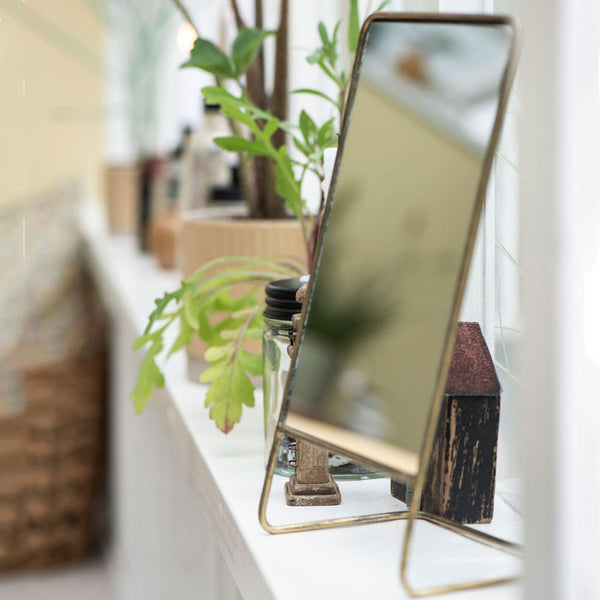 Brass dressing table mirror on a shelf