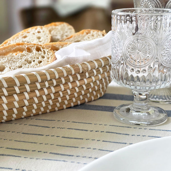 Bread in a basket with decorative glassware on a tablecloth