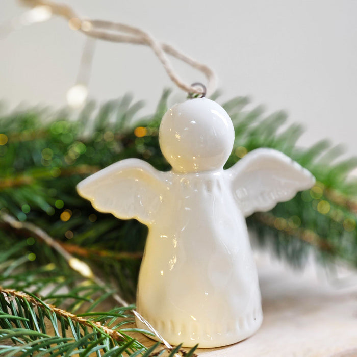 White ceramic angel Christmas tree decoration with tree foliage.