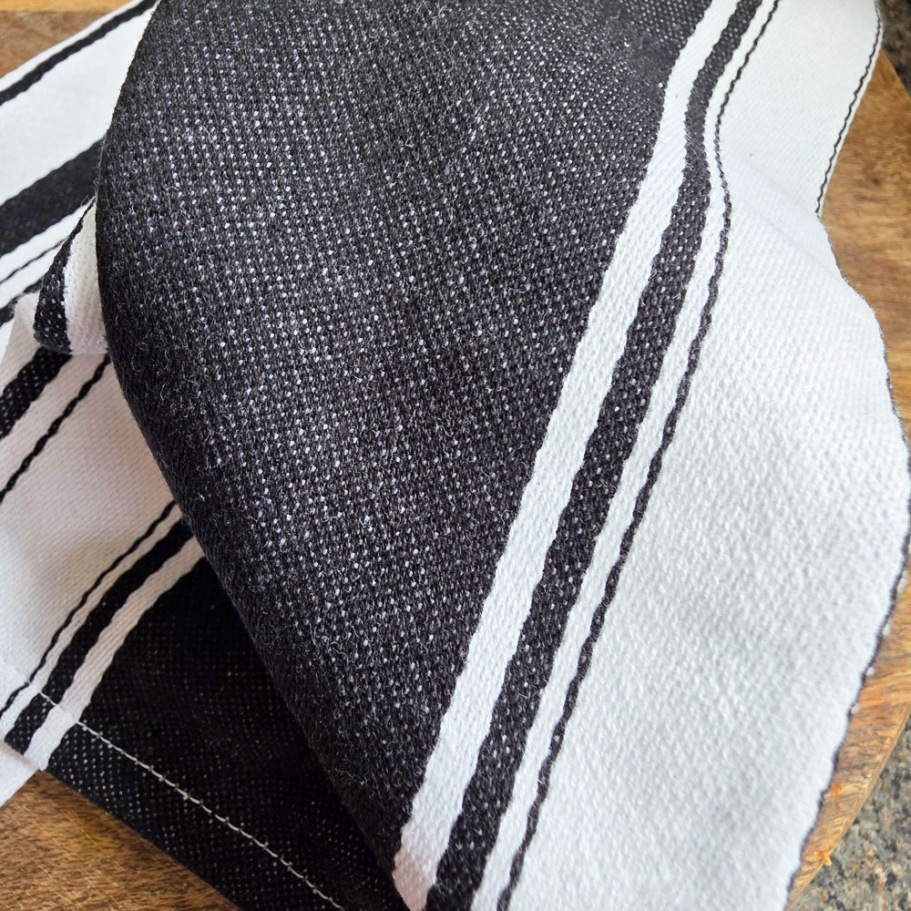 Close-up of a black and white striped cotton tea towel on a wooden surface