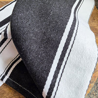 Close-up of a black and white striped cotton tea towel on a wooden surface