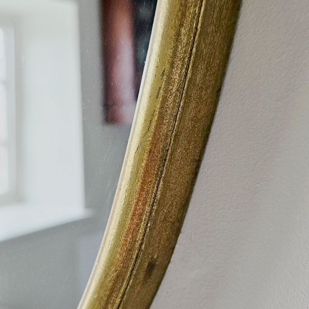Close-up of a gold mirror frame on a neutral background