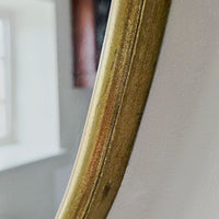 Close-up of a gold mirror frame on a neutral background