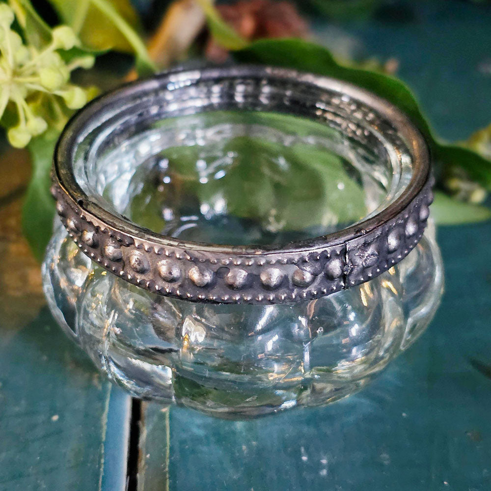 Clear glass pumpkin tea light holder with metallic band on a green background