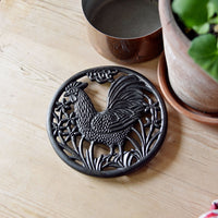 Cast iron cockerel trivet on kitchen table