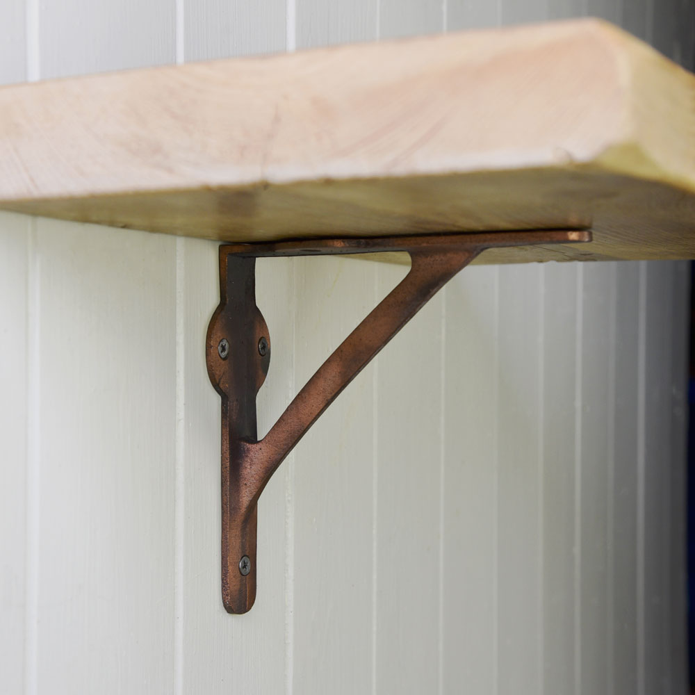 Copper wall shelf bracket supporting rustic shelf board