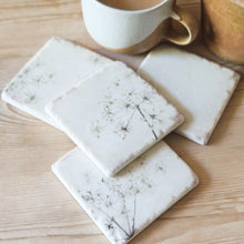 Four cow parsley drinks coasters on a kitchen table.