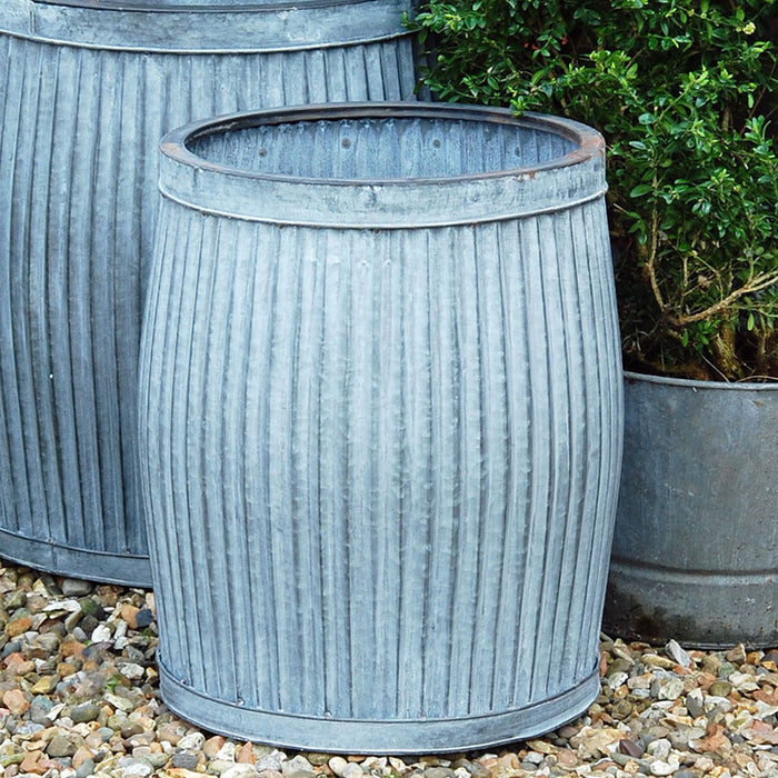 Galvanised metal garden planter on a gravel yard.