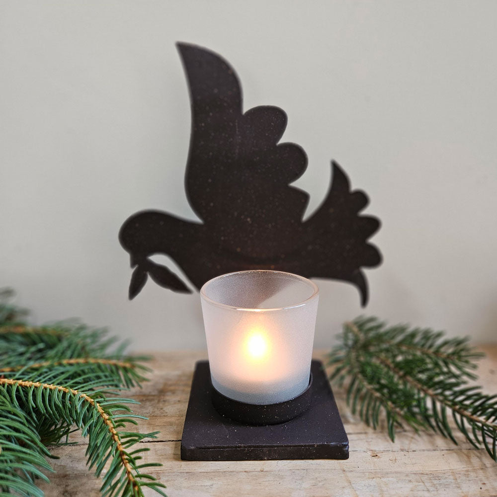 Dove silhouette tea light holder surrounded by Christmas foliage 