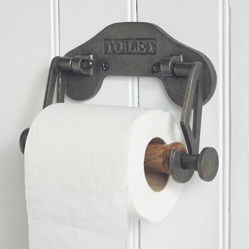 Vintage-style metal toilet paper holder with wooden core against a white paneled wall.