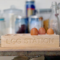 Wooden egg holder labeled 'Egg Station' with eggs on a kitchen counter.