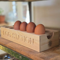 Wooden egg holder with 'Egg Station' branding on a wooden surface.