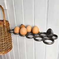 Decorative egg holder with eggs on a white wooden wall, next to a wicker basket.