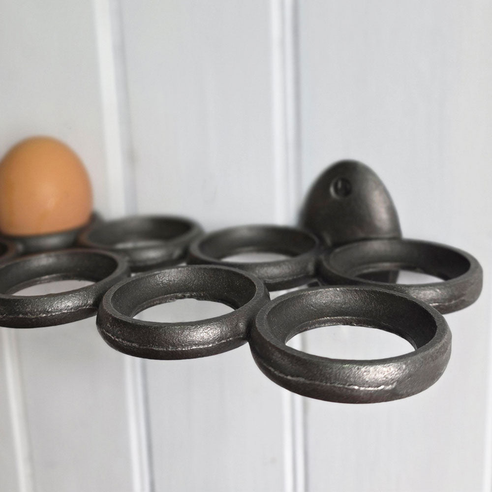 Grey metal egg holder with a brown egg on a white wooden background