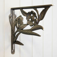 Decorative cast iron shelf bracket with floral design on a white wooden background
