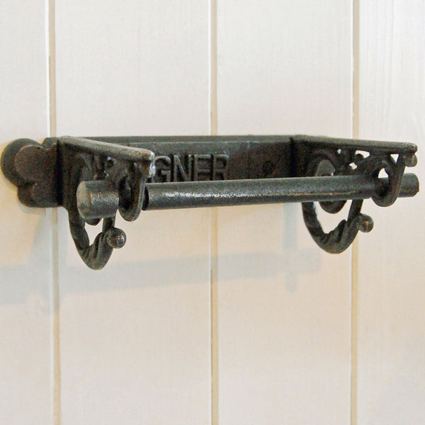 GNER vintage wall mounted cast iron toilet roll holder, against cream wooden panelled wall