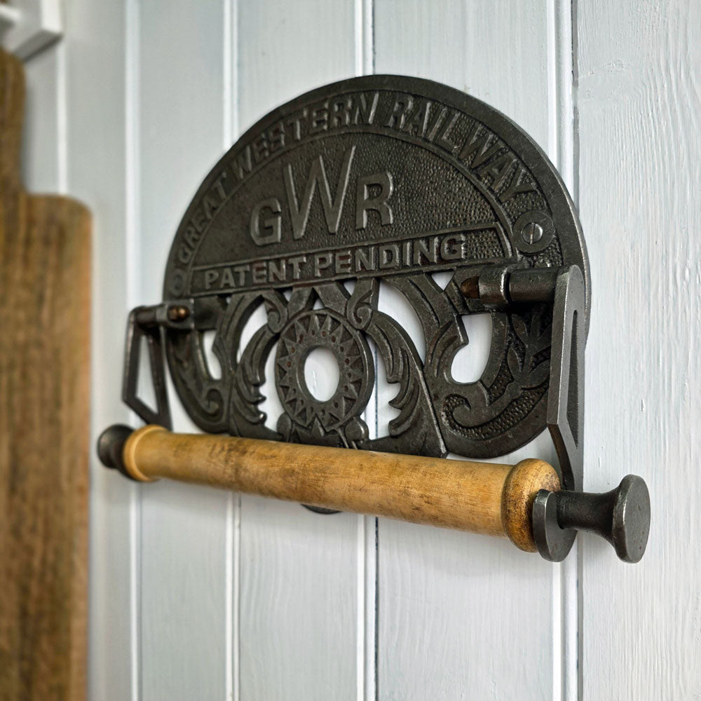 Decorative toilet paper holder with 'GWR' branding on a white wooden panel background