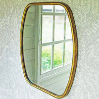 Gold chateau wall mirror against a wall papered wall