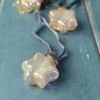 Vintage gold glass star Christmas decorations on a blue wooden table.