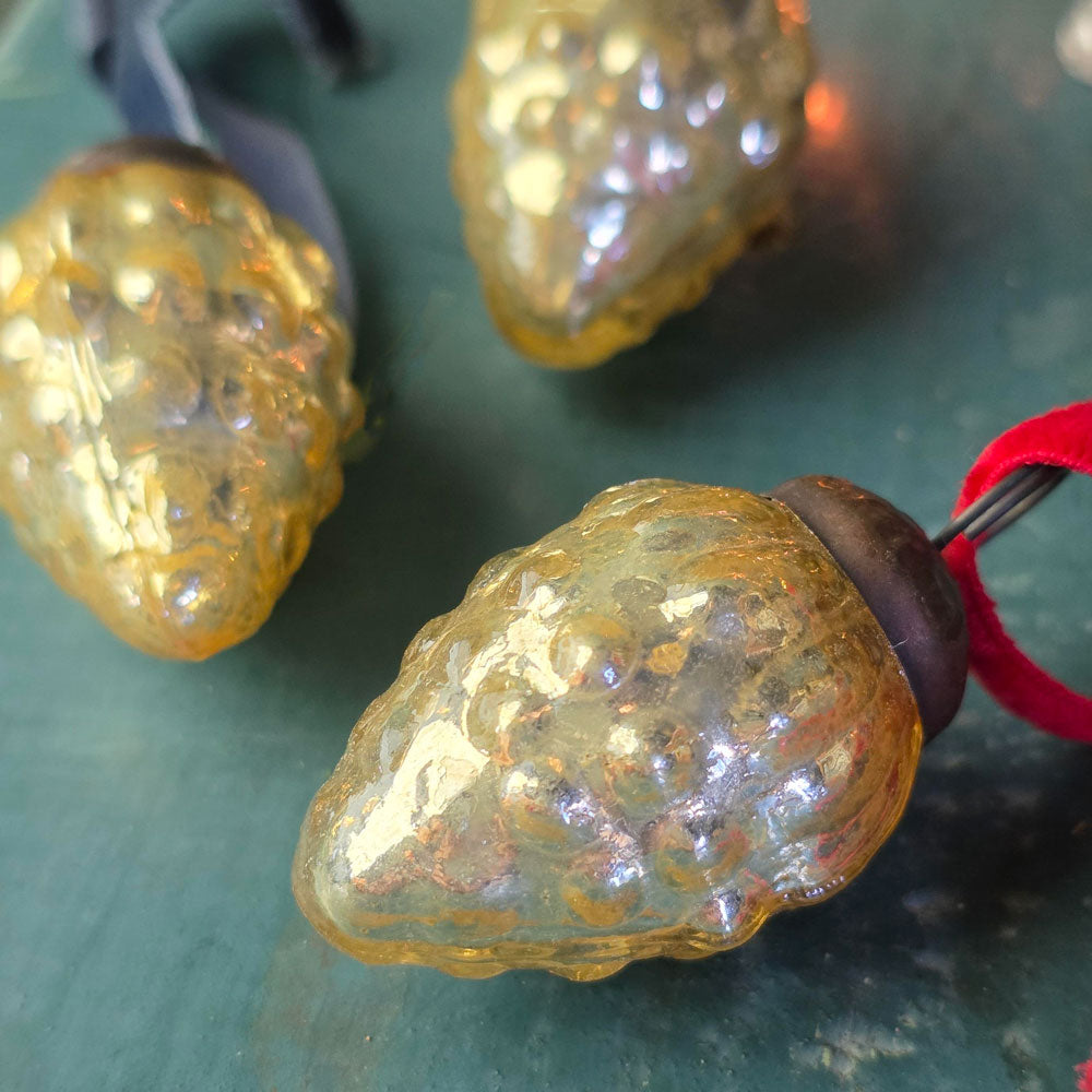 Three antique glass Christmas baubles on a blue wooden surface