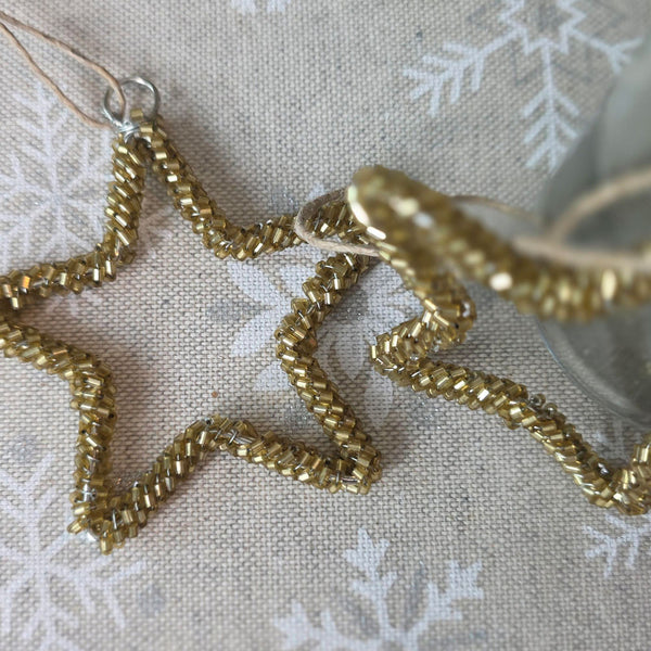 Gold beaded star decorations on a snowflake patterned tablecloth.