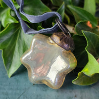 Gold glass star Christmas decoration on a blue velvet ribbon decoration.