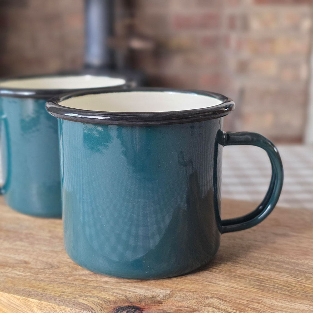 Close up of a green enamel mug on a wooden board.