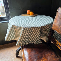 Checkered tablecloth on a wooden table with a chair in a room.