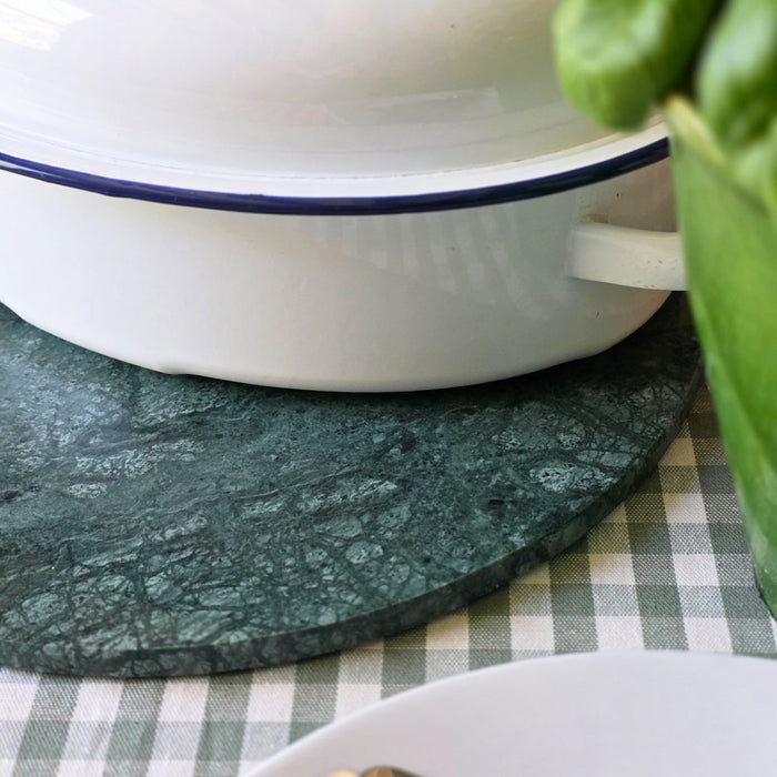 White bowl with blue rim on a green marble serving board over a checkered wipe-clean tablecloth