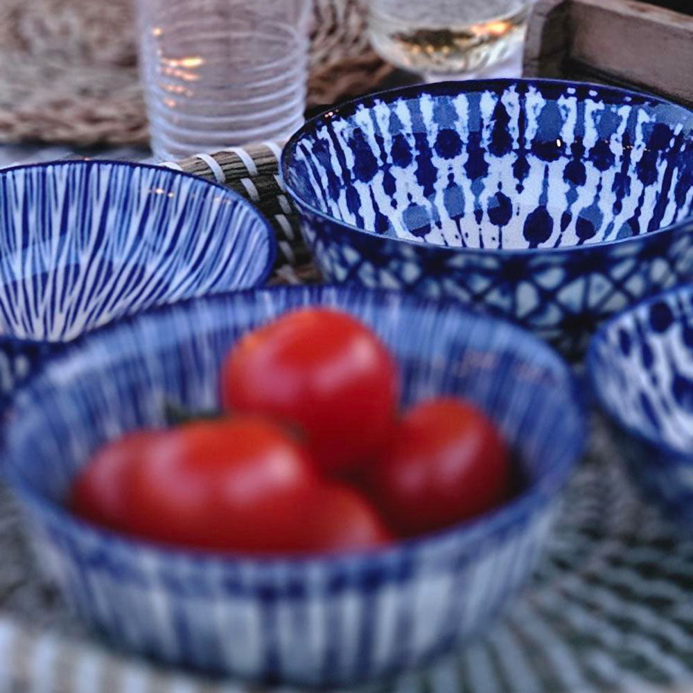 Blue and white patterned bowls with red tomatoes on a textured surface