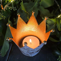Crown-shaped tea light holder with a lit tea light on a dark background