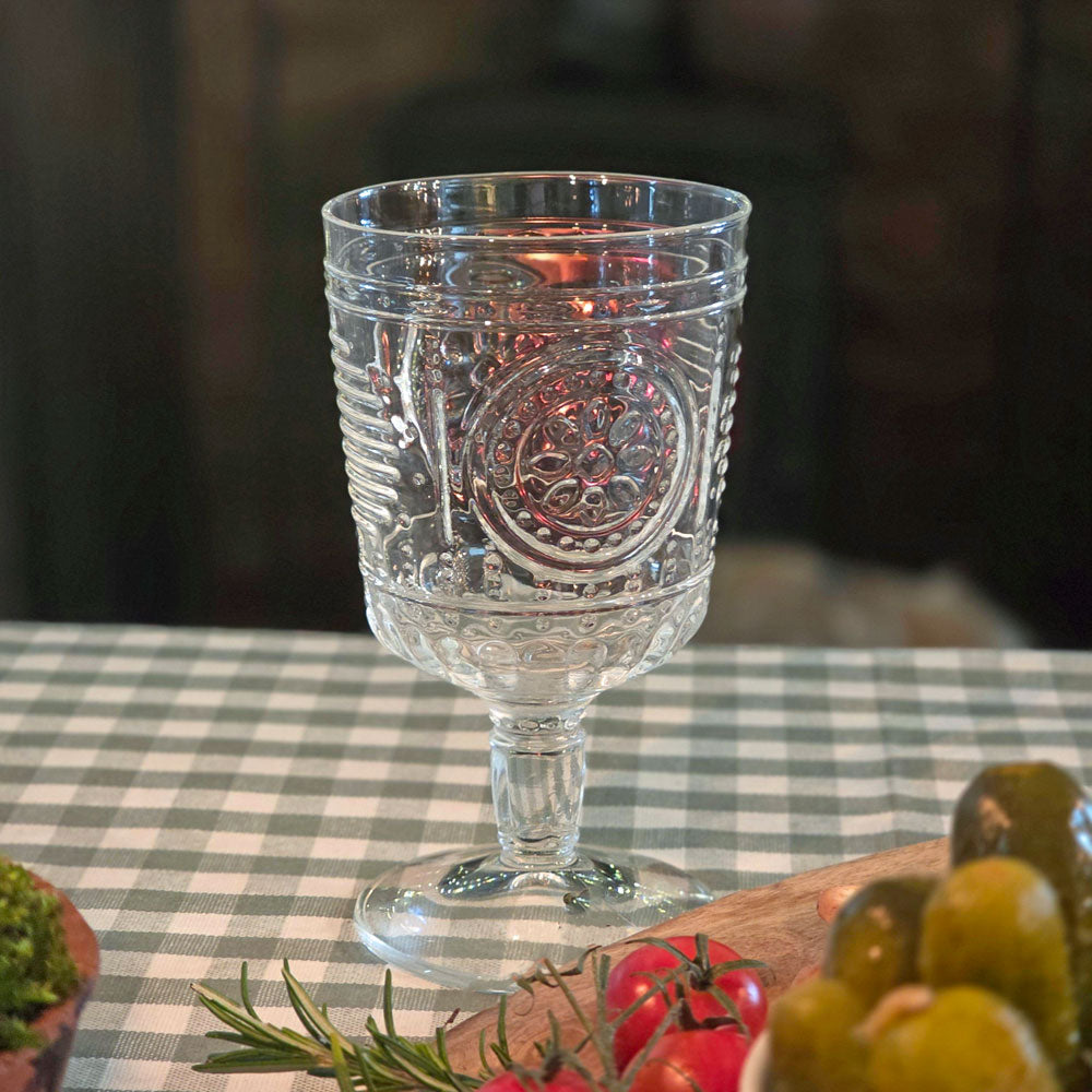 Italian wine glass on a table covered with green gingham tablecloth  and fresh vegetables.
