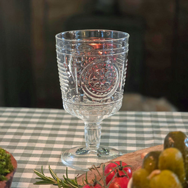 Italian wine glass on a table covered with green gingham tablecloth  and fresh vegetables.