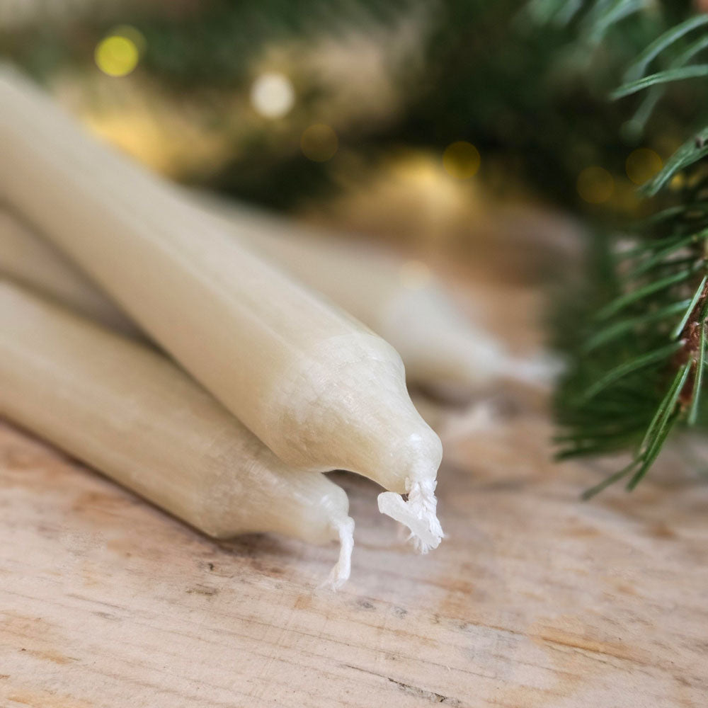 Khaki green Danish dinner candles next to Christmas foliage