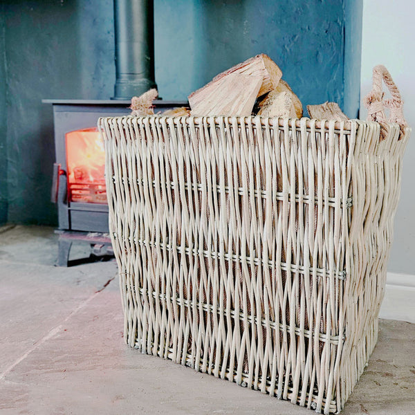 Large Belper wicker log basket next to a wood burning stove.