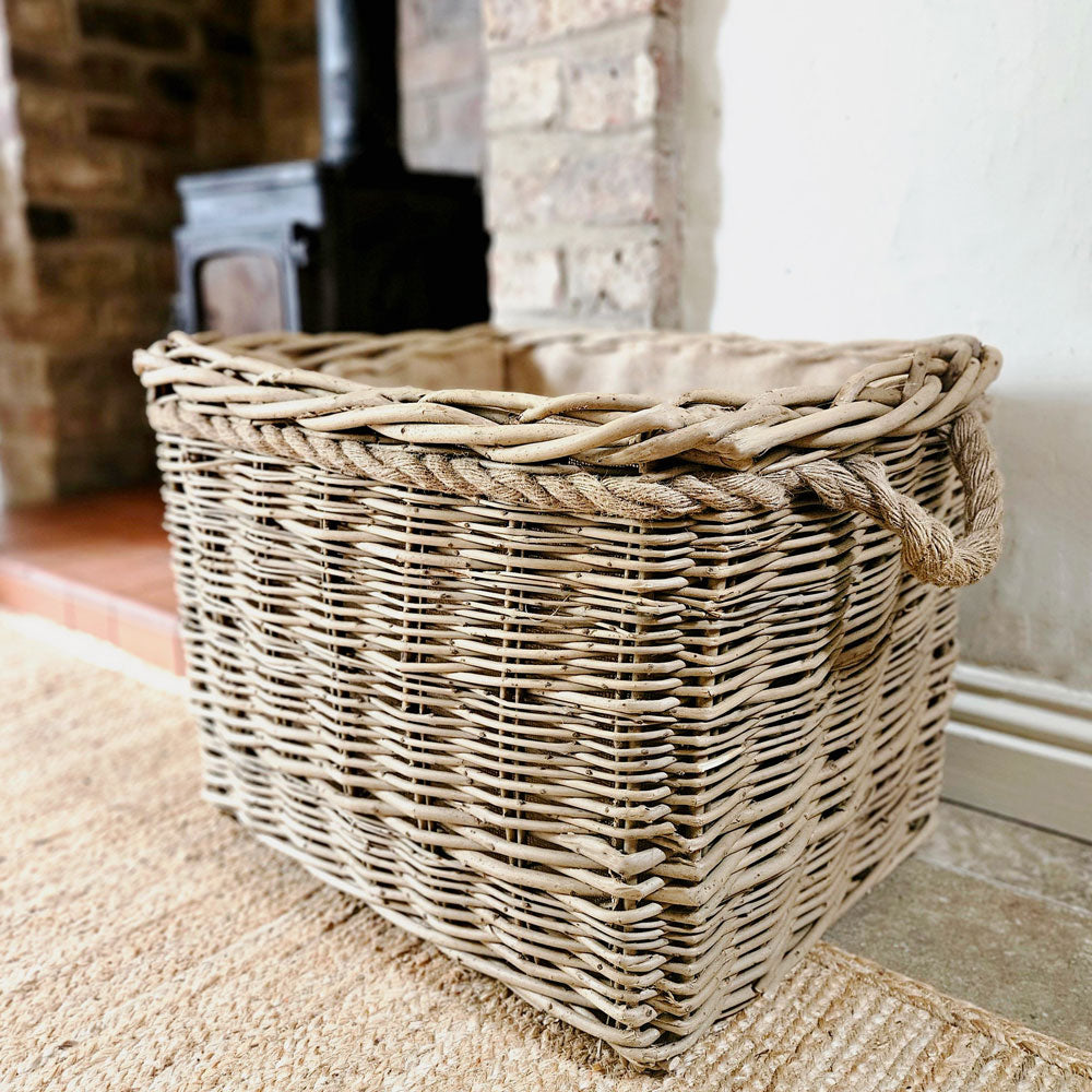 Large wicker mill style log basket next to wood burning stove.