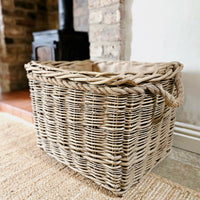 Large wicker mill style log basket next to wood burning stove.