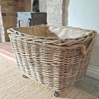 Wicker log basket with wheels on a carpeted floor.